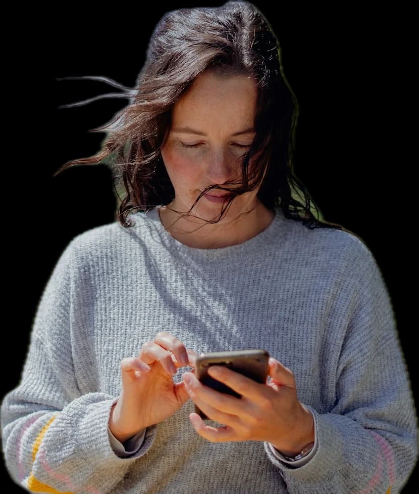 A woman with windswept hair tapping on her phone