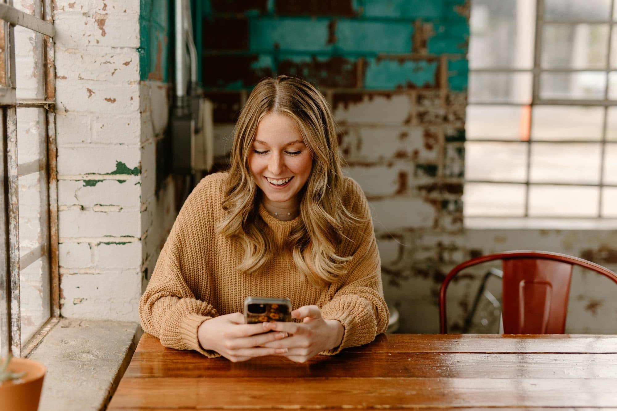A business owner smiling at her phone at a café table
